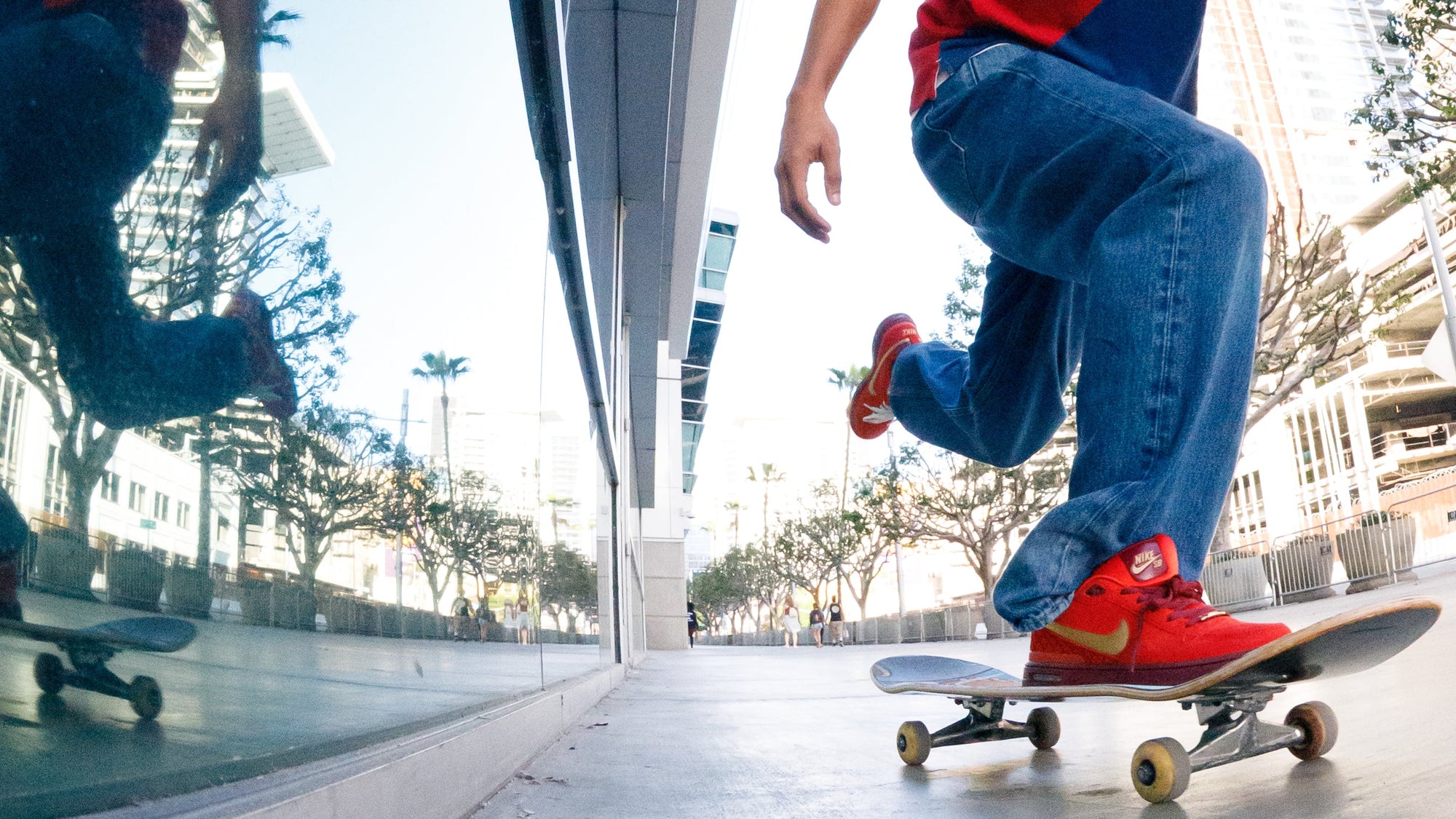 Skateboarder performing a trick on a city street with modern buildings in the background